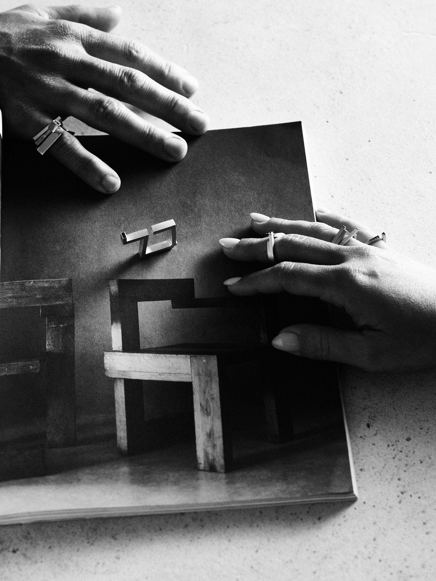 Black and white photo of hands holding a book with geometric wood models.