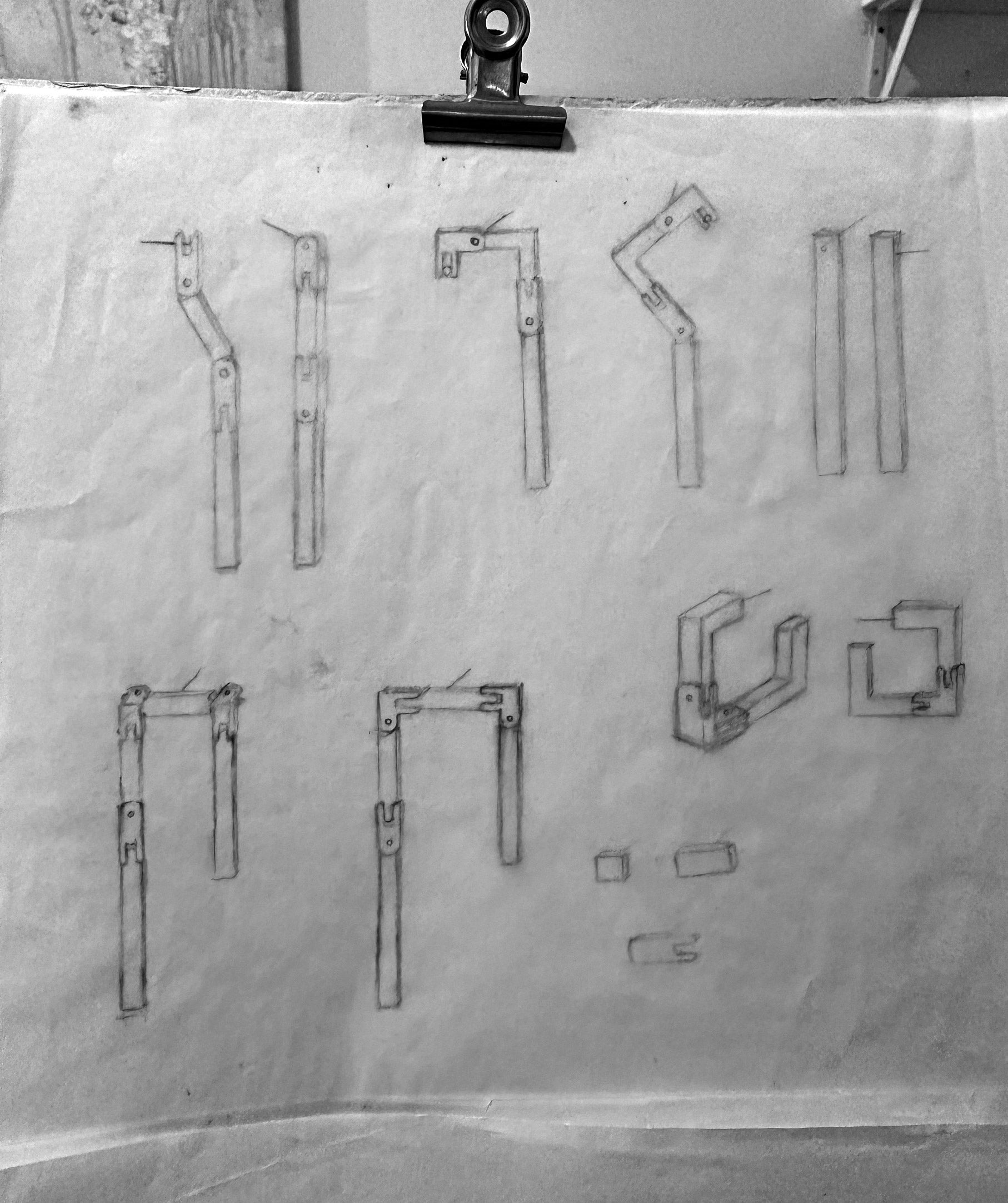 Technical drawings of metal brackets on a white sheet with a black clip.